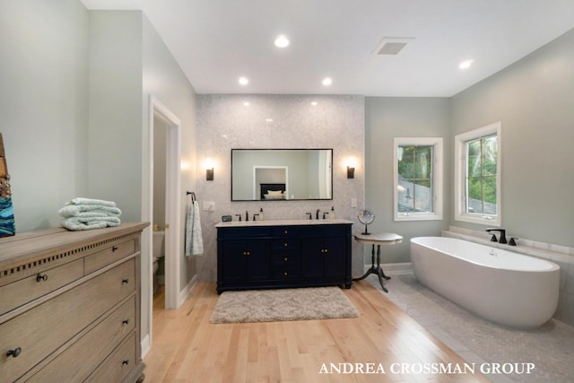 41 Bay Meadows Dr, Holland, MI 49424 - full bath with double vanity, a freestanding tub, wood finished floors, and recessed lighting
