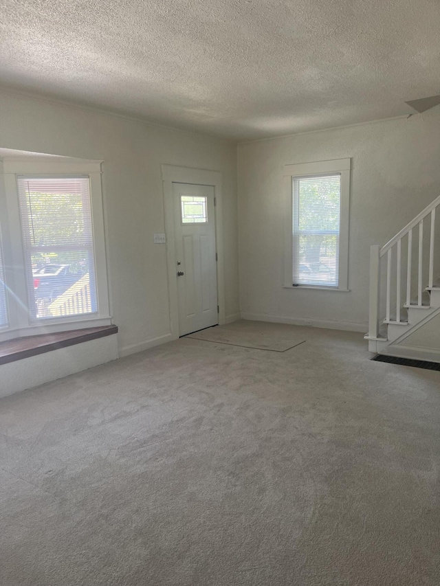 515 Hall St SE, Grand Rapids, MI 49507 - carpeted foyer featuring stairs, a textured ceiling, and plenty of natural light