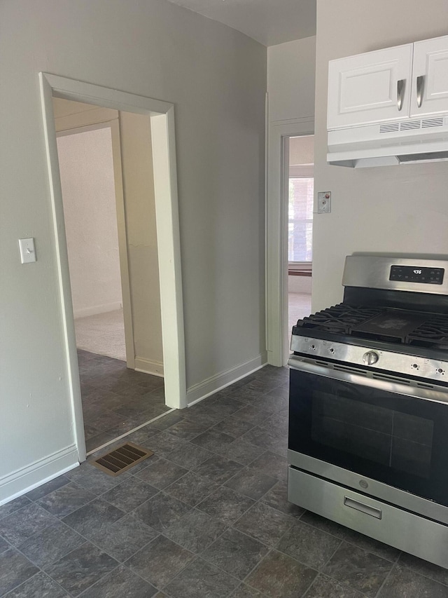 515 Hall St SE, Grand Rapids, MI 49507 - kitchen with stainless steel gas range, under cabinet range hood, dark stone finish flooring, and white cabinetry