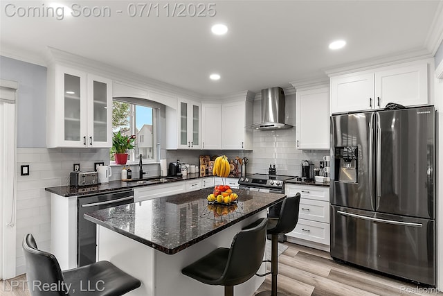 17952 Marsal Dr, Macomb, MI 48042 - kitchen featuring appliances with stainless steel finishes, wall chimney range hood, a breakfast bar, white cabinetry, and recessed lighting