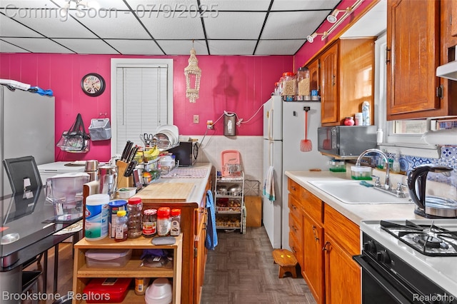 3831 Casmere St, Hamtramck, MI 48212 - kitchen with black microwave, light countertops, brown cabinetry, a drop ceiling, and freestanding refrigerator