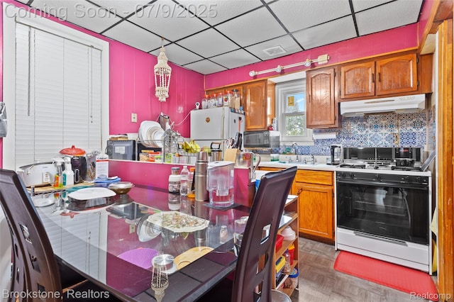 3831 Casmere St, Hamtramck, MI 48212 - kitchen with gas stove, a paneled ceiling, freestanding refrigerator, under cabinet range hood, and light countertops