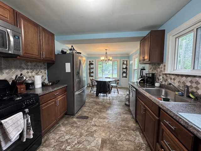 2728 Brook Dr, Kalamazoo, MI 49004 - kitchen with stainless steel appliances, dark countertops, a chandelier, decorative backsplash, and pendant lighting