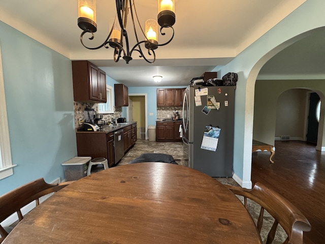 2728 Brook Dr, Kalamazoo, MI 49004 - dining space with arched walkways, a chandelier, and dark wood finished floors