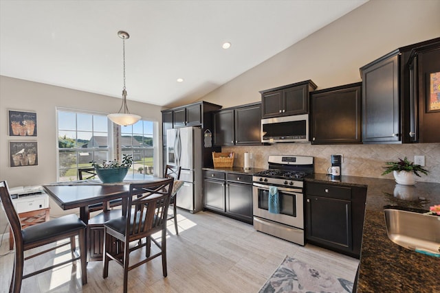 58852 Silvergrass Dr, Mattawan, MI 49071 - kitchen featuring stainless steel appliances, lofted ceiling, backsplash, decorative light fixtures, and dark stone counters