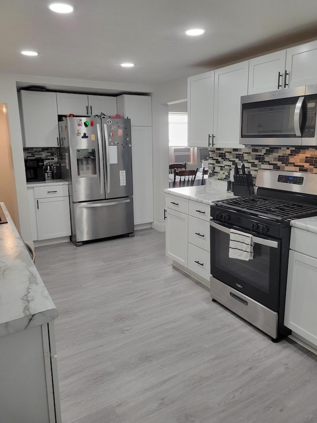 1211 Howard Ave, Muskegon, MI 49442 - kitchen with stainless steel appliances, decorative backsplash, white cabinets, light wood-style flooring, and recessed lighting