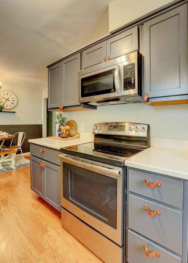 1441 Lewison Ave NE, Grand Rapids, MI 49505 - kitchen with stainless steel appliances, gray cabinetry, light countertops, light wood-style floors, and a wainscoted wall