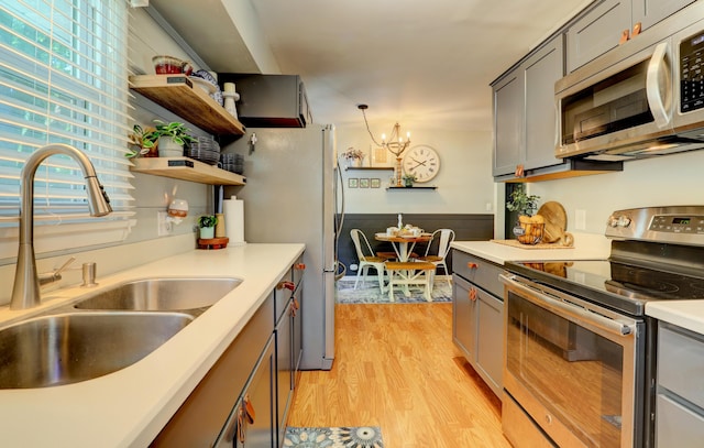 1441 Lewison Ave NE, Grand Rapids, MI 49505 - kitchen with stainless steel appliances, a chandelier, light wood-style flooring, gray cabinets, and light countertops