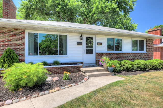 1441 Lewison Ave NE, Grand Rapids, MI 49505 - view of front of property with a chimney, brick siding, and a front lawn