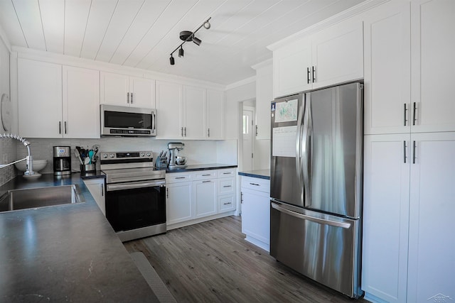 514 Hunter St, Saginaw, MI 48602 - kitchen featuring stainless steel appliances, dark countertops, backsplash, dark wood-type flooring, and white cabinetry