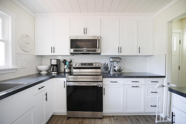 514 Hunter St, Saginaw, MI 48602 - kitchen featuring stainless steel appliances, dark countertops, white cabinets, decorative backsplash, and wood finished floors