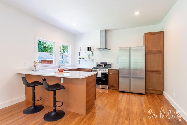 68 E River Rd, Muskegon, MI 49445 - kitchen featuring stainless steel appliances, ventilation hood, brown cabinetry, a peninsula, and light wood finished floors