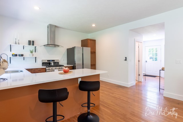 68 E River Rd, Muskegon, MI 49445 - kitchen featuring appliances with stainless steel finishes, island range hood, open shelves, a kitchen breakfast bar, and light wood-type flooring