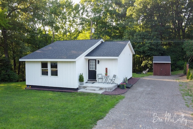 68 E River Rd, Muskegon, MI 49445 - view of front of property with a storage shed, a shingled roof, a front lawn, covered porch, and driveway