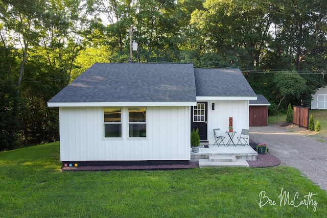68 E River Rd, Muskegon, MI 49445 - view of front of home with roof with shingles, a front yard, an outdoor structure, and driveway