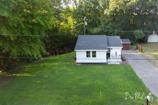 68 E River Rd, Muskegon, MI 49445 - view of front facade with an outbuilding, a front lawn, roof with shingles, and driveway