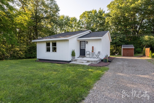 68 E River Rd, Muskegon, MI 49445 - view of front of home with gravel driveway, a storage shed, a front lawn, and roof with shingles