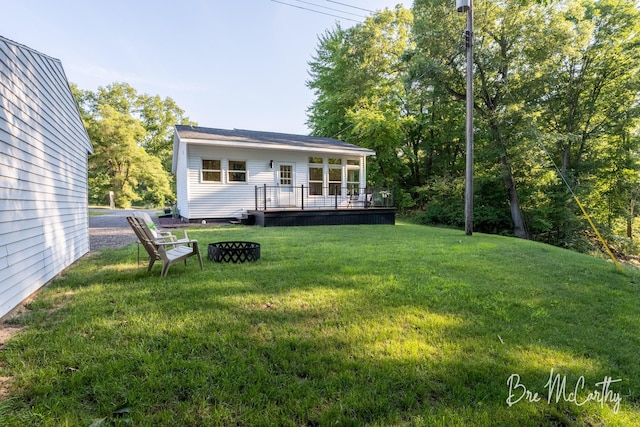 68 E River Rd, Muskegon, MI 49445 - rear view of property featuring a wooden deck, a lawn, and a fire pit