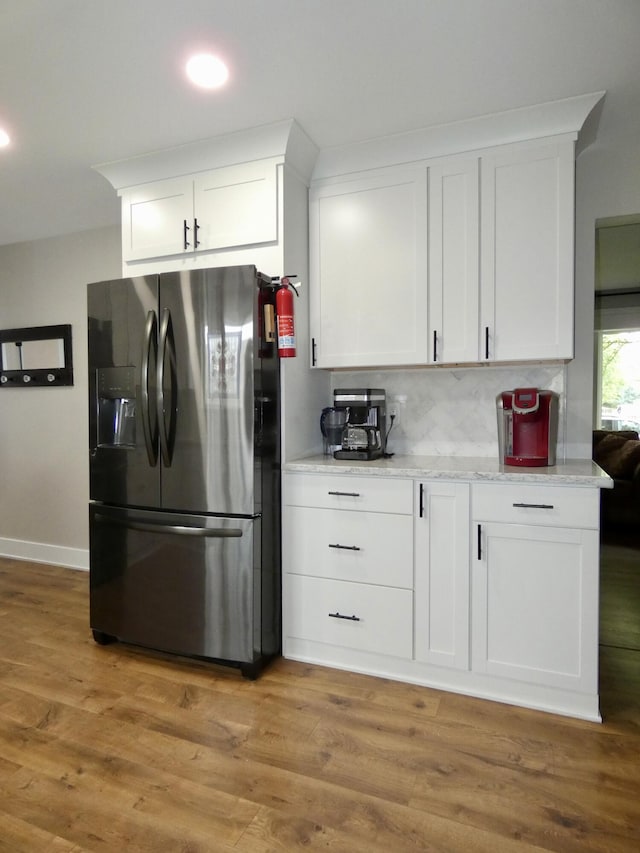 630 Forest St, Wyandotte, MI 48192 - kitchen featuring stainless steel refrigerator with ice dispenser, backsplash, white cabinetry, and light wood-style floors