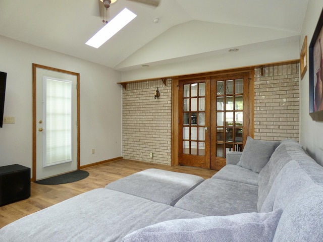 630 Forest St, Wyandotte, MI 48192 - living room featuring wood finished floors, vaulted ceiling, a skylight, and brick wall