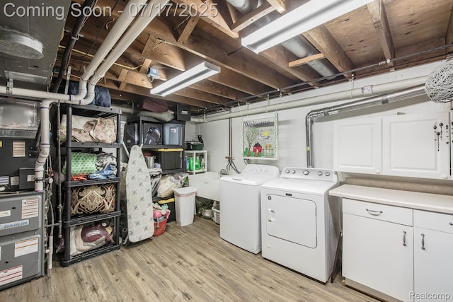 5074 Perryville Rd, Holly, MI 48442 - washroom with washing machine and clothes dryer, cabinet space, light wood-style flooring, and heating unit
