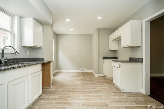 17344 Wisconsin St, Detroit, MI 48221 - kitchen featuring light wood finished floors, dark stone countertops, recessed lighting, and white cabinetry