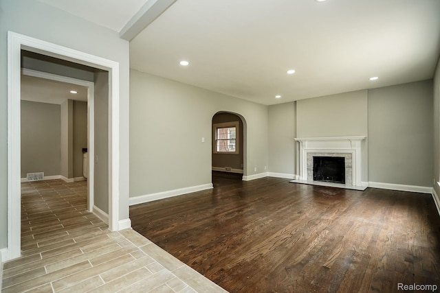 17344 Wisconsin St, Detroit, MI 48221 - unfurnished living room featuring arched walkways, wood finished floors, recessed lighting, and a fireplace with flush hearth