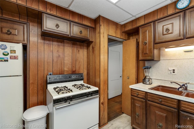 1536 Glynn Ct, Detroit, MI 48206 - kitchen with white appliances, light countertops, wooden walls, and brown cabinetry
