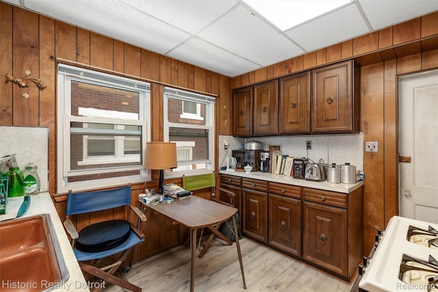 1536 Glynn Ct, Detroit, MI 48206 - kitchen with light countertops, wood walls, light wood finished floors, gas range gas stove, and an office area
