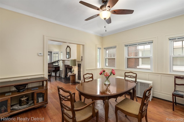 1536 Glynn Ct, Detroit, MI 48206 - dining space featuring a ceiling fan, crown molding, wood finished floors, a wainscoted wall, and a decorative wall