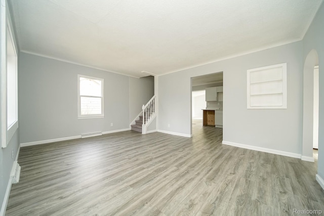 967 Keith St, Oxford, MI 48371 - unfurnished living room featuring wood finished floors, stairway, arched walkways, and built in features
