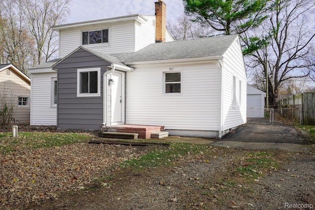 967 Keith St, Oxford, MI 48371 - rear view of house with a chimney, a garage, and roof with shingles