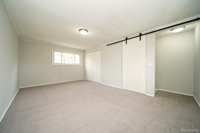 967 Keith St, Oxford, MI 48371 - unfurnished bedroom with a barn door, light carpet, and a textured ceiling