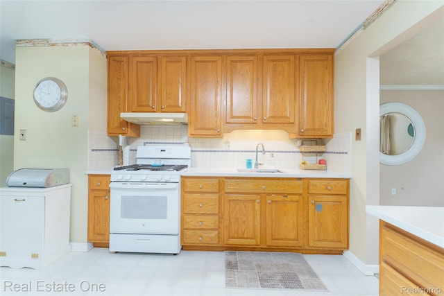 5320 Leland St, Brighton, MI 48116 - kitchen with white gas range, under cabinet range hood, light countertops, backsplash, and ornamental molding