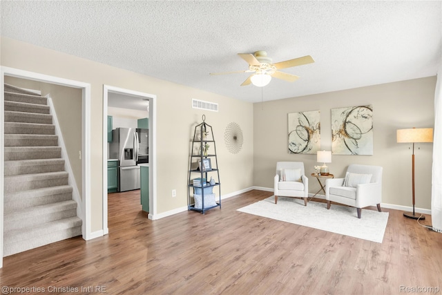 61374 Dean Dr, South Lyon, MI 48178 - living area featuring a ceiling fan, stairway, wood finished floors, and a textured ceiling