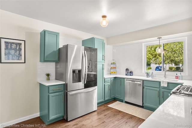 61374 Dean Dr, South Lyon, MI 48178 - kitchen featuring appliances with stainless steel finishes, decorative backsplash, wood finished floors, light countertops, and hanging light fixtures