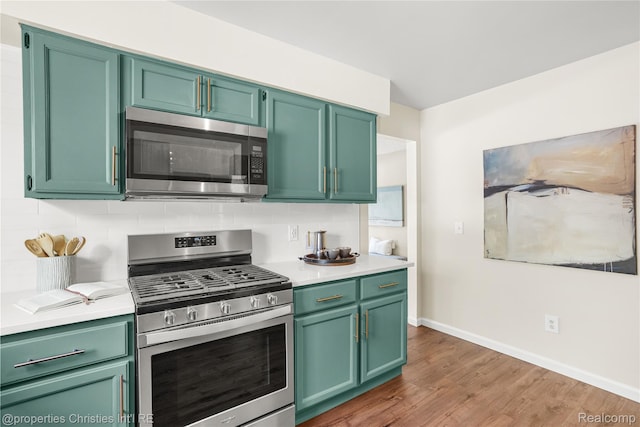 61374 Dean Dr, South Lyon, MI 48178 - kitchen with stainless steel appliances, light countertops, wood finished floors, green cabinets, and tasteful backsplash