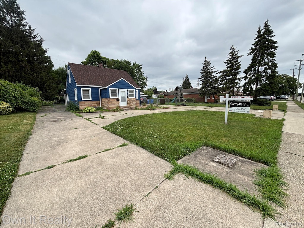 5696 Kinloch St, Dearborn Heights, MI 48127 - view of front of home featuring a front yard, a chimney, stone siding, concrete driveway, and roof with shingles