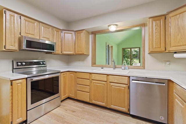 7184 Steeplechase Dr, Saline, MI 48176 - kitchen featuring appliances with stainless steel finishes, light brown cabinetry, light wood-style floors, light countertops, and vaulted ceiling