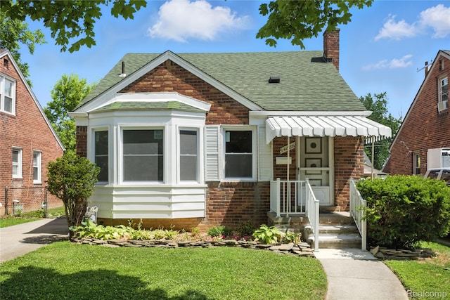 14888 Belmont Ave, Southgate, MI 48101 - bungalow-style house featuring roof with shingles, brick siding, a front yard, and a chimney
