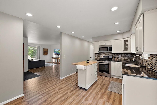9950 Carpenter Rd, Milan, MI 48160 - kitchen featuring appliances with stainless steel finishes, tasteful backsplash, a center island, light wood-type flooring, and dark countertops
