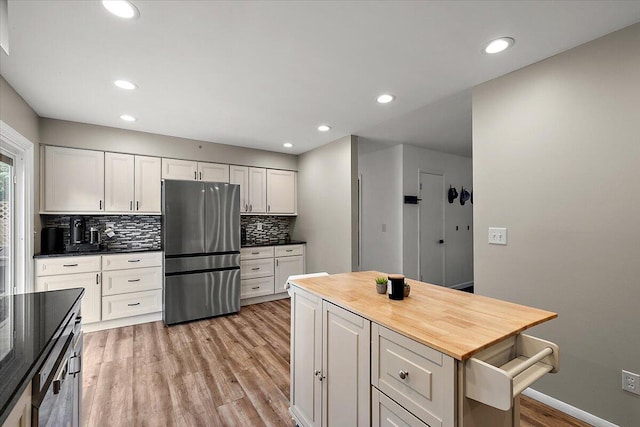 9950 Carpenter Rd, Milan, MI 48160 - kitchen featuring freestanding refrigerator, light wood-style flooring, decorative backsplash, recessed lighting, and white cabinets