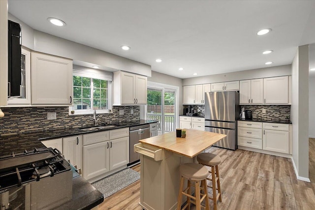 9950 Carpenter Rd, Milan, MI 48160 - kitchen with stainless steel appliances, light wood-style flooring, decorative backsplash, white cabinetry, and a kitchen bar