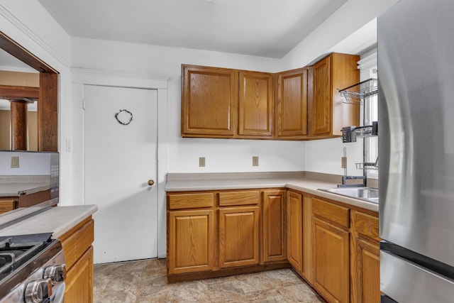 843 Center St, Jackson, MI 49202 - kitchen featuring appliances with stainless steel finishes, light countertops, brown cabinetry, and stone finish flooring