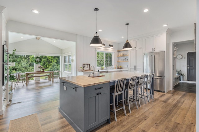 8608 52nd St SE, Ada, MI 49301 - kitchen with high end refrigerator, vaulted ceiling, a kitchen island with sink, gray cabinetry, and white cabinets