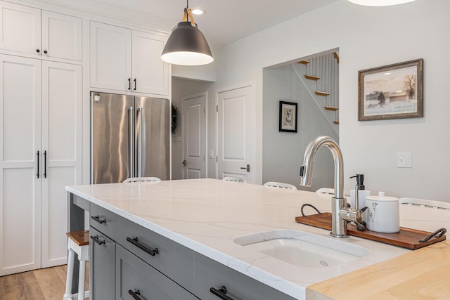 8608 52nd St SE, Ada, MI 49301 - kitchen with high end fridge, gray cabinets, light stone countertops, pendant lighting, and light wood-type flooring