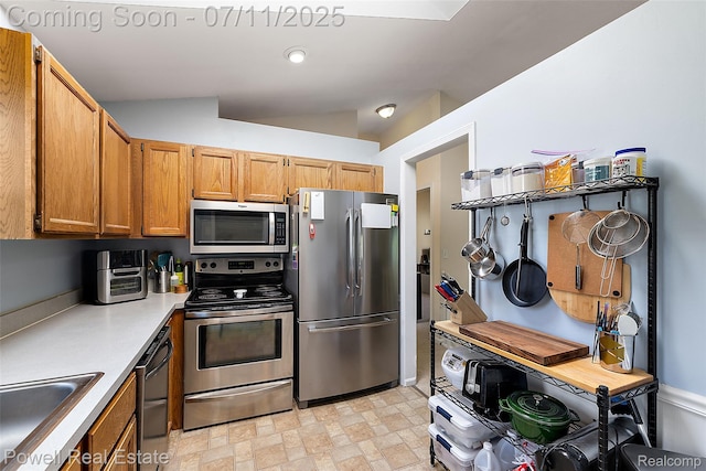 2601 Eardman Ct, Westland, MI 48186 - kitchen featuring appliances with stainless steel finishes, light countertops, vaulted ceiling, and brown cabinetry