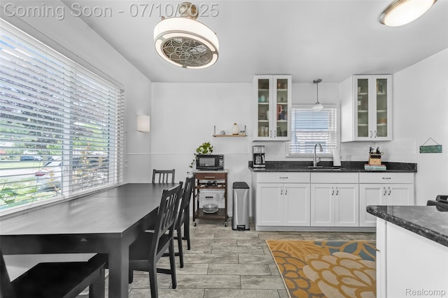 2216 Barrett Ave, Royal Oak, MI 48067 - kitchen featuring black microwave, white cabinetry, glass insert cabinets, hanging light fixtures, and dark stone countertops