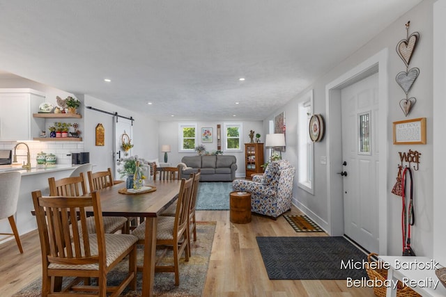 10840 Harvard Ave NE, Rockford, MI 49341 - dining area featuring a barn door, light wood-style floors, and recessed lighting