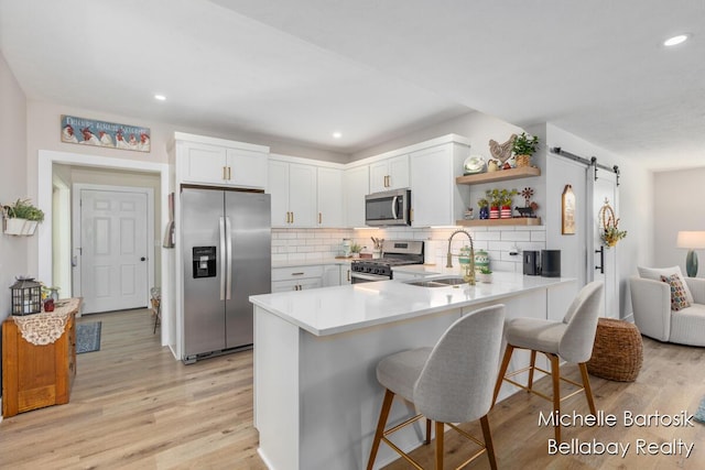 10840 Harvard Ave NE, Rockford, MI 49341 - kitchen with stainless steel appliances, a peninsula, open shelves, light wood-style floors, and decorative backsplash